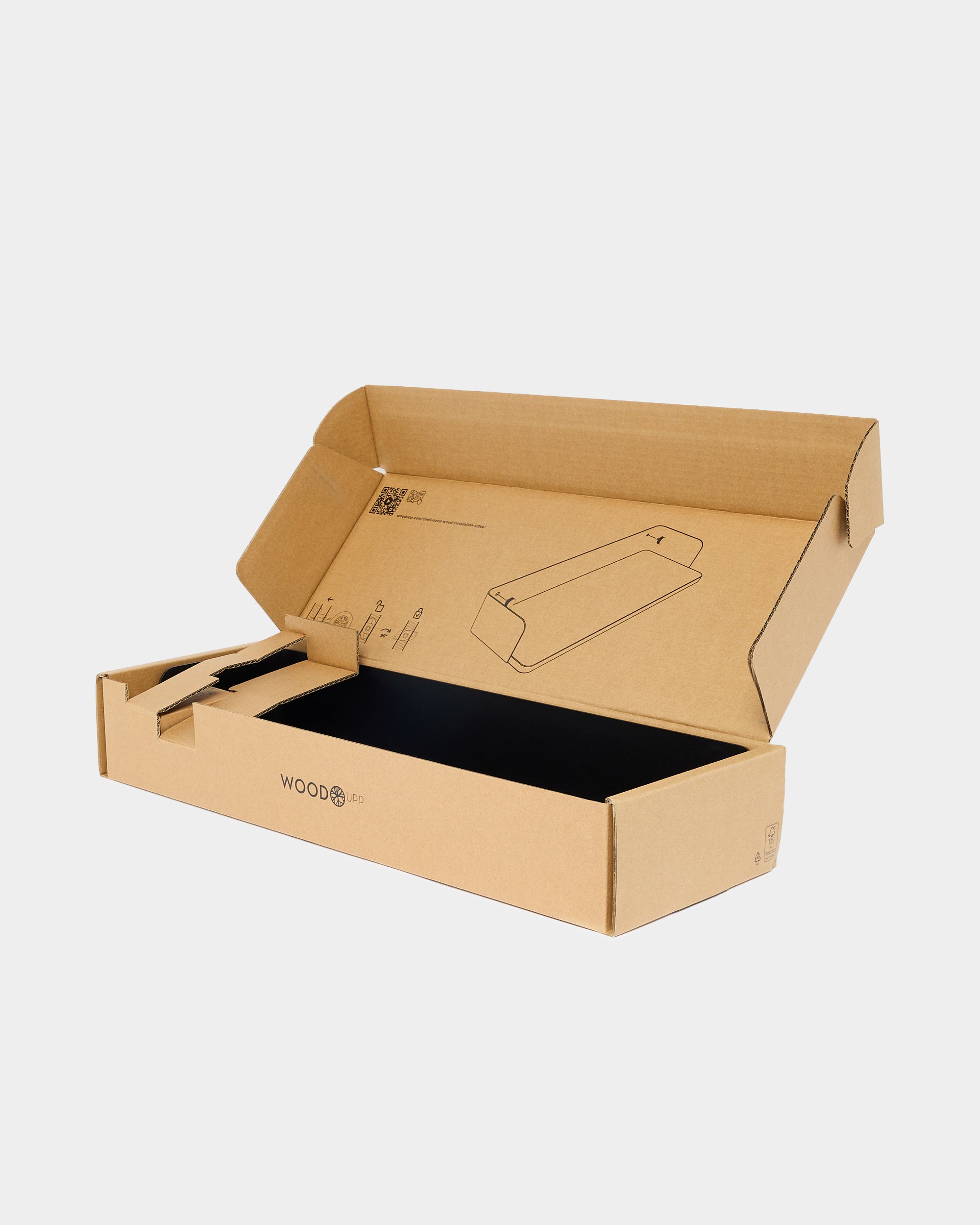 Open brown WoodUpp packaging box with black interior and printed assembly drawings on plain light-grey background